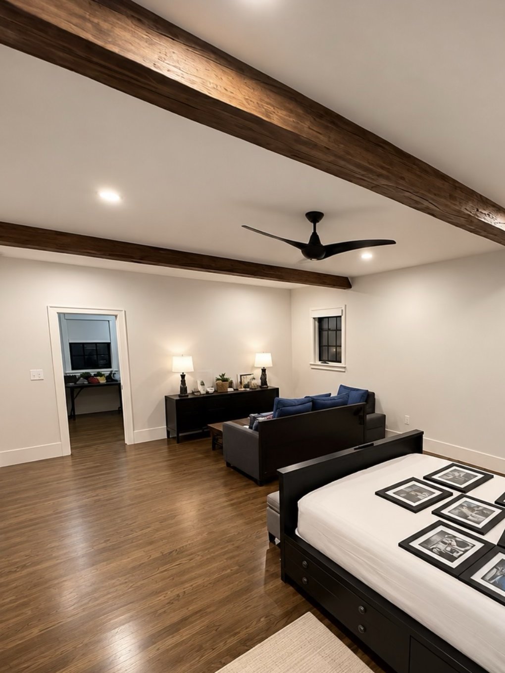 Bedroom with smooth white walls and ceiling, exposed wood beams and crisp white trim