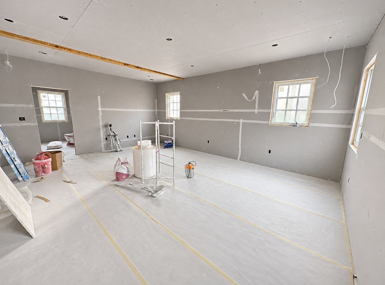 Room with new drywall taped and floors protected during renovation