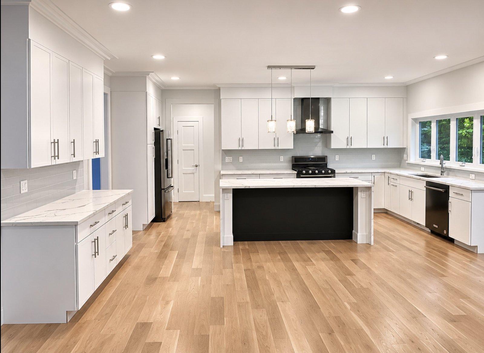 Bright white shaker kitchen with black island, quartz countertops and light oak floors
