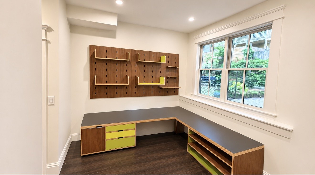 Custom built-in L-shaped desk with drawers, open shelves and wood pegboard wall