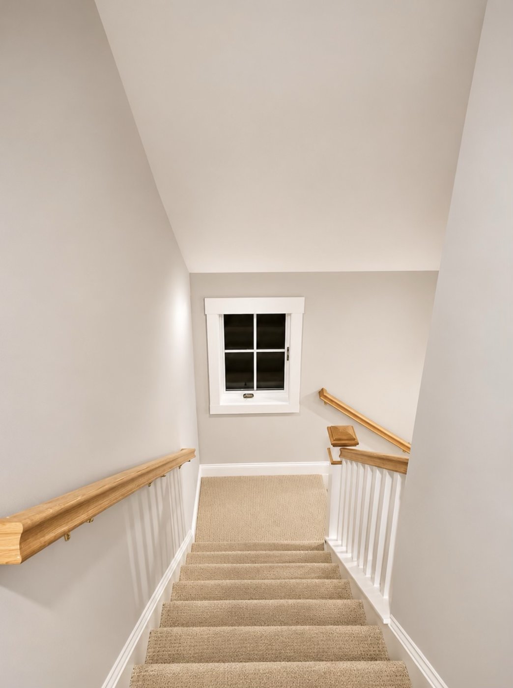 Painted stairwell with white trim, white balusters and oak handrails