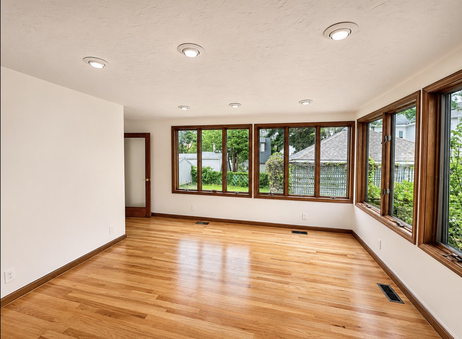 Sunroom with freshly painted white walls and ceiling and stained wood window trim